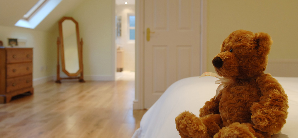 Teddy bear on bed in loft conversino bedroom